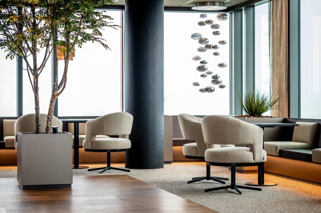 Moderne en sfeervolle wachtruimte met beige fauteuils, kunstplanten en grote ramen op de P.J. Oudweg.